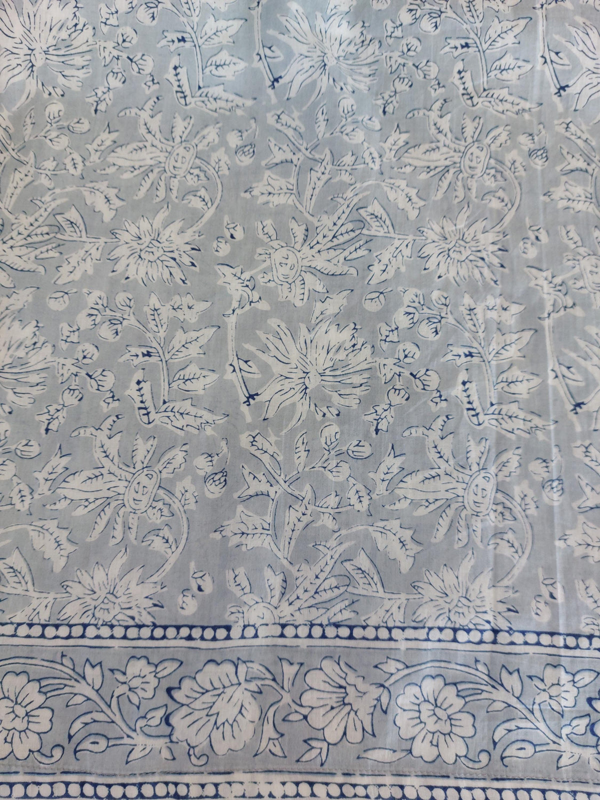 Détail du tissu et des finitions : robe ample en coton blanc et gris, pompons bleus