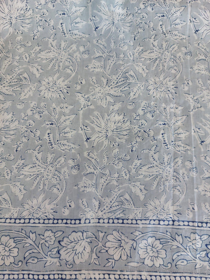Détail du tissu et des finitions : robe ample en coton blanc et gris, pompons bleus