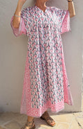 Peut inclure: Longue robe à imprimé floral blanc et rose avec manches courtes. La robe présente un col en V et une silhouette ample et fluide. Les manches et l'ourlet sont bordés d'une bordure géométrique rose. La robe est en tissu léger, idéale pour l'été.